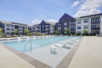 a swimming pool with lounge chairs in front of an apartment building